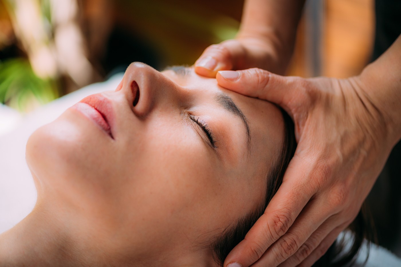 Craniosacral-Behandlung – Julia Grosse legt sanft die Hände an den Kopf einer liegenden Klientin